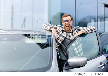 Great Car. Cheerful guy standing near autoand smiling, buying vehicle in dealership center 120116510