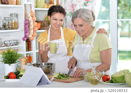 Elderly woman with her daughter cooking in the kitchen 120116531