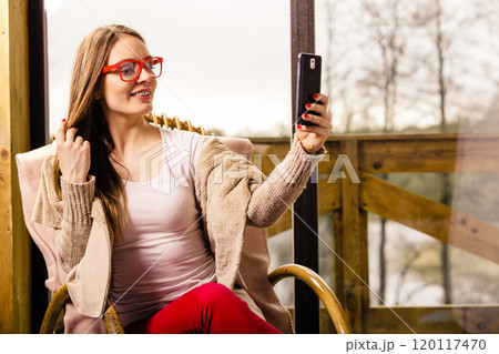 Woman sitting on chair making selfie at home 120117470