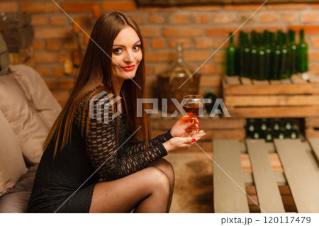 Woman tasting wine in rural cottage interior 120117479