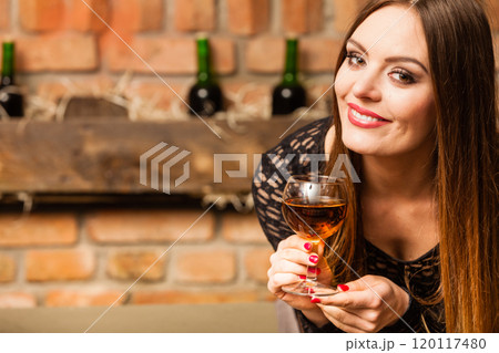 Woman tasting wine in rural cottage interior 120117480