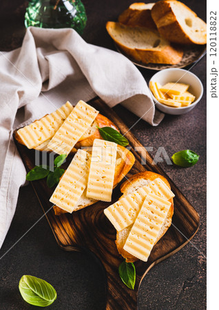 Fried bread toasts with cheese and basil on a board on the table vertical view 120118822