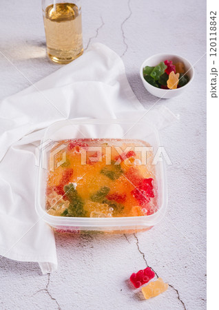 Marmalade candies are infused in lemonade for subsequent freezing in a container vertical view 120118842