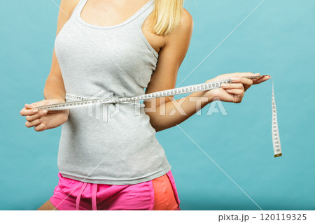 Fitness girl measuring her waistline Fitness girl measuring her waistline 120119325