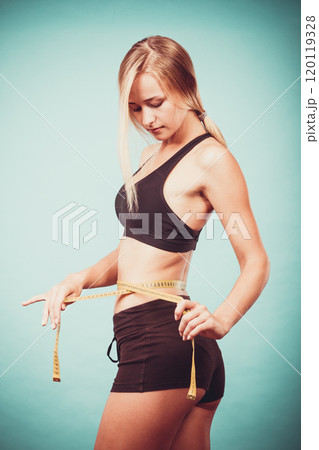 Fitness girl measuring her waistline Fitness girl measuring her waistline 120119328