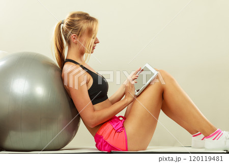 Fit woman sitting on floor with tablet pc 120119481