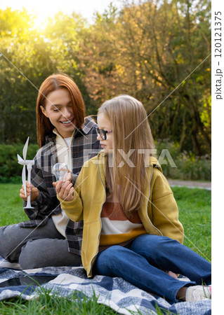 Little girl with teacher in park observing wind turbines learning about eco-friendly power sources 120121375