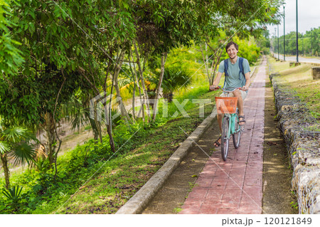 Man tourist cycling through the charming village of Bacalar, Mexico. Quintana Roo travel, scenic bike paths, and eco-friendly exploration concept 120121849