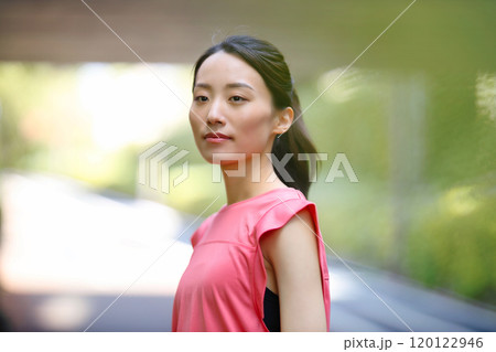 緑の中に佇むスポーツウエアの若い女性 120122946