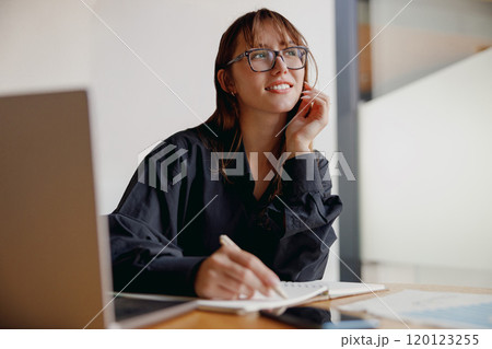 A Thoughtful Woman Dressed in a Black Shirt Diligently Working on a Project Assignment A Thoughtful Woman Dressed in a Black Shirt Diligently Working on a Project Assignment 120123255