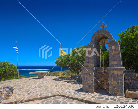 礼拝所の鐘撞堂と海風に靡くギリシャ国旗、双頭の鷲の旗 (ギリシャ、クレタ島、コロキタ) 120124930