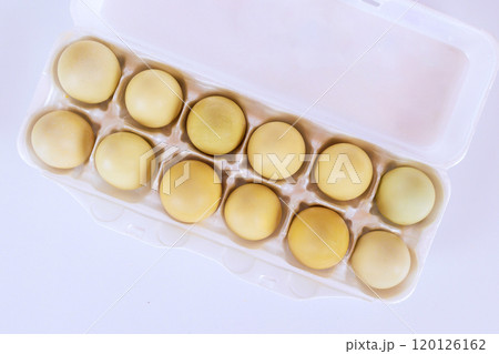 An egg carton containing twelve yellow eggs ready for cooking, baking 120126162