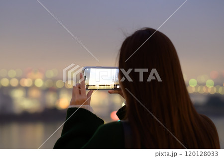 冬のお台場の夜景をスマホで撮影する女性 120128033