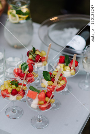 A table with glasses of fruit and a bottle of champagne 120128247
