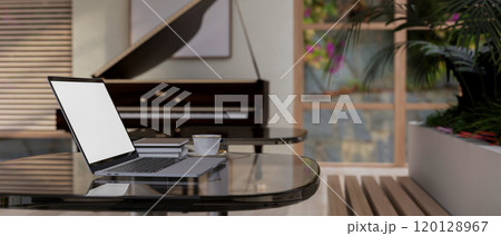 A laptop on a table in a luxurious restaurant with a grand piano in the background. 120128967