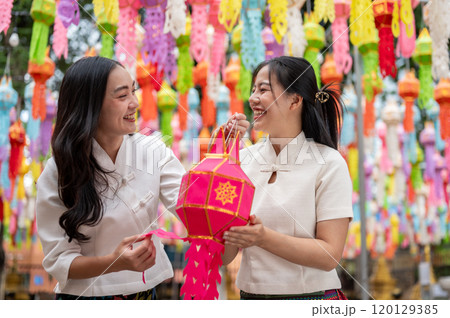 Two Asian women hold a lantern together, enjoying a traditional lantern festival at a temple. 120129385
