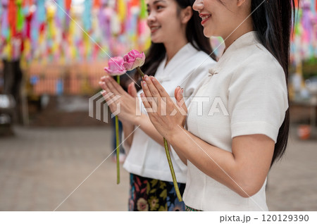 A close-up of two beautiful Asian women praying at a temple during a traditional festival. A close-up of two beautiful Asian women praying at a temple during a traditional festival. 120129390