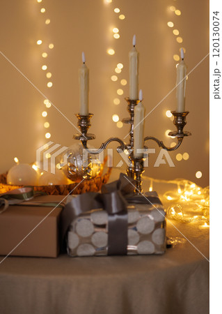 A table with three candles and two gift boxes 120130074