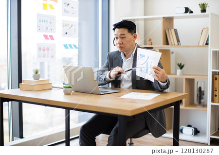 Asian businessman in headset conducts online presentation with graphs 120130287