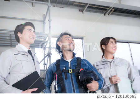 作業を着たゼネコン系の人とデニムを着た現場監督など未来や目標、希望を見上げる3人 現場のITやdx化 120130665