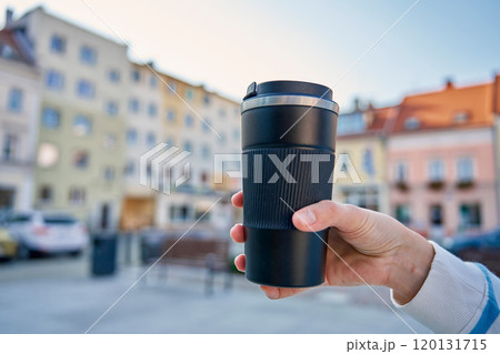 Woman holding reusable coffee cup outdoors in autumn Woman holding reusable coffee cup outdoors in autumn 120131715