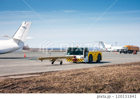 Tow tractor with towbar and tank truck aircraft refuelers moves at the airport apron 120131841