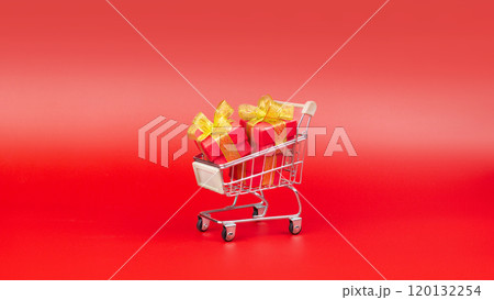 Supermarket trolley, with red gifts. Buying gifts for Sale, Discounts, Black Friday, New Year, Christmas, Birthday and Valentines day. On a red background, minimal design Supermarket trolley, with red gifts. Buying gifts for Sale, Discounts, Black Friday, New Year, Christmas, Birthday and Valentines day. On a red background, minimal design 120132254