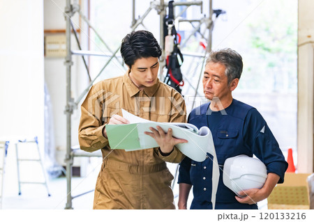 工事現場で相談する大工と作業員 120133216