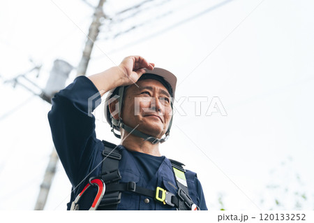 電柱の前に立つシニア作業員 120133252