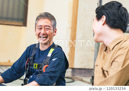 工事現場で談笑する大工と作業員 120133256