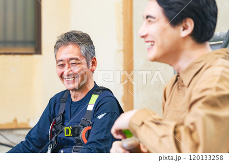 工事現場で談笑する大工と作業員 120133258