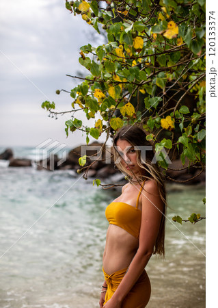 Enjoy a Serene Beach Walk A Woman in a Beautiful Yellow Dress Strolling by the Ocean Shore 120133374