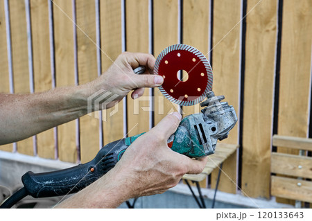 Replaceable diamond blade for cutting stone and concrete is installed on an angle grinder. 120133643