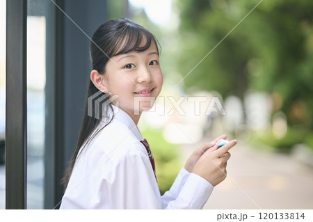 バス停でスマートフォンを見る女子中学生 120133814