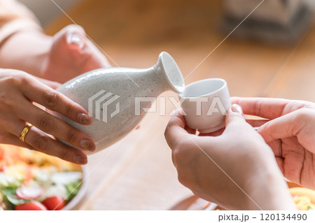 日本酒・冷酒・熱燗をお酌する女性の手元 日本酒・冷酒・熱燗をお酌する女性の手元 120134490
