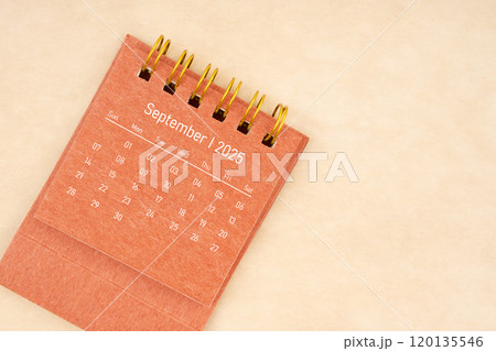 Mini red desk calendar for September 2025 year on old brown paper background. 120135546