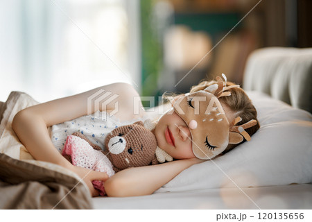 child is sleeping in the bed 120135656