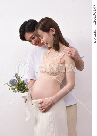 妊娠した若い妻と花束を持って寄り添う夫 120136147