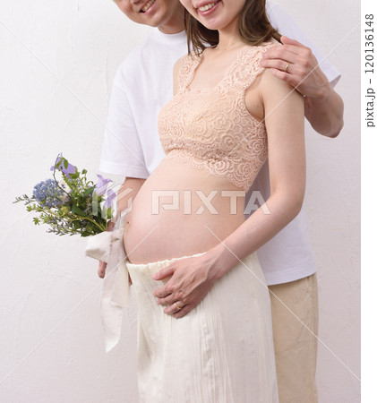妊娠した若い妻と花束を持って寄り添う夫 120136148