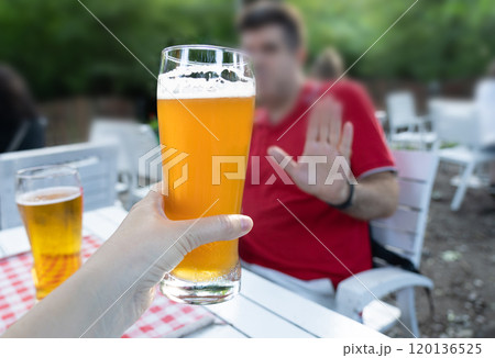 Reject a glass of beer, woman refusing alcohol, stop drinking, sobriety concept, saying no to beer glass 120136525