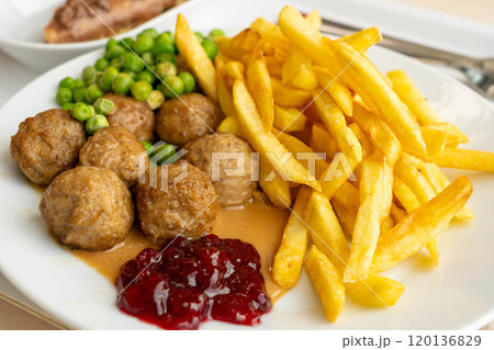 Meatballs with french fries, green peas, bechamel sauce and cranberry jam, meat balls on white plate Meatballs with french fries, green peas, bechamel sauce and cranberry jam, meat balls on white plate 120136829