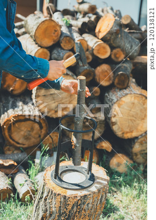 薪割り台に薪を置いてハンマーで叩く 薪割り台に薪を置いてハンマーで叩く 120138121