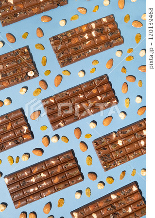 Lots of chocolate bars with nuts and raisins on a blue background top view. Lots of chocolate bars with nuts and raisins on a blue background top view. 120139468