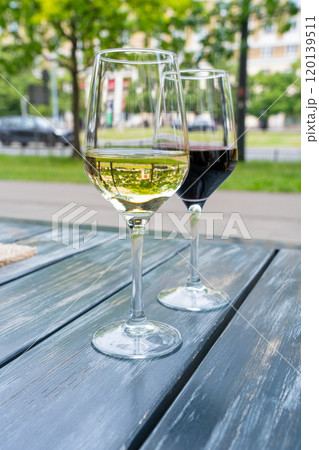 Red wine and white wine glass on restaurant table, wineglasses dinner on restaurant summer terrace Red wine and white wine glass on restaurant table, wineglasses dinner on restaurant summer terrace 120139511