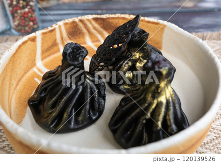 Black khinkali, Georgian seafood chinkali, spicy dumplings with minced meat also called dimsum Black khinkali, Georgian seafood chinkali, spicy dumplings with minced meat also called dimsum 120139526