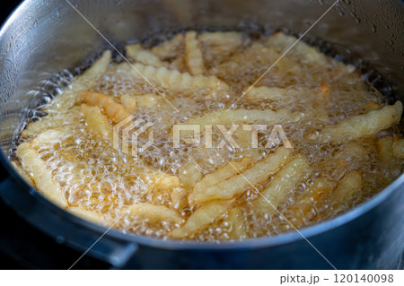 Potatoes in boiling oil, homemade french fries, deep fried potato cooking in metal fryer pot, fat fast food 120140098