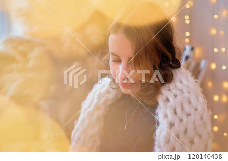 teenage girl in a dress near an unconventional Christmas tree surrounded by golden lights 120140438
