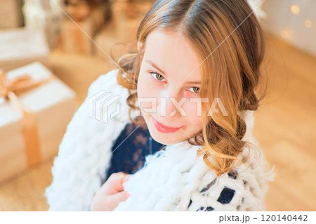 teenage girl in a dress near an unconventional Christmas tree surrounded by golden lights teenage girl in a dress near an unconventional Christmas tree surrounded by golden lights 120140442