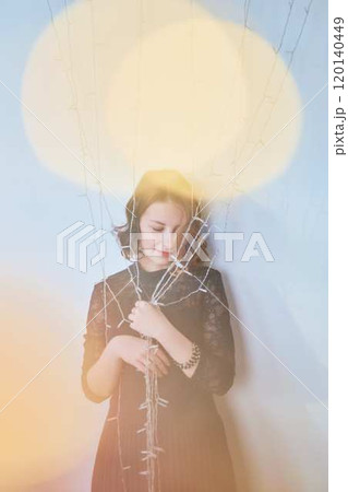 a teenage girl in a dress surrounded by golden Christmas lights 120140449
