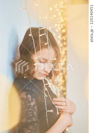 a teenage girl in a dress surrounded by golden Christmas lights 120140451